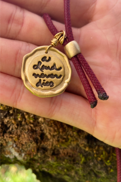 Plum Village pendant with ‘A Cloud Never Die’ mantra against a tree